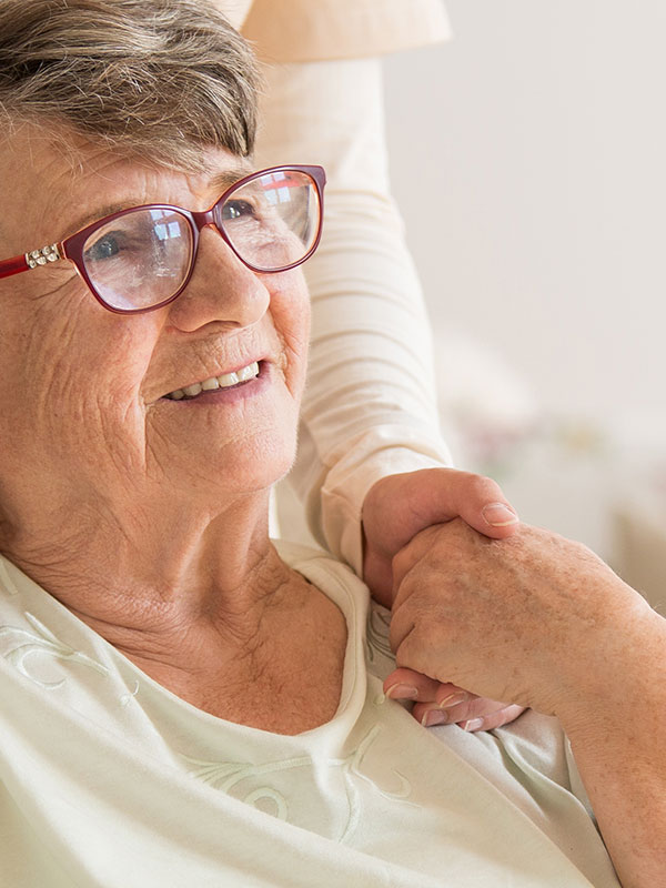 Eine Pflegekraft hält einfühlsam die Hand einer Seniorin im Hanse-Zentrum, der familiären Pflege-Einrichtung in Soest.