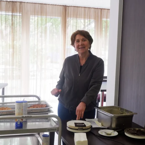 Eine Frau backt Waffeln und lächelt in die Kamera.