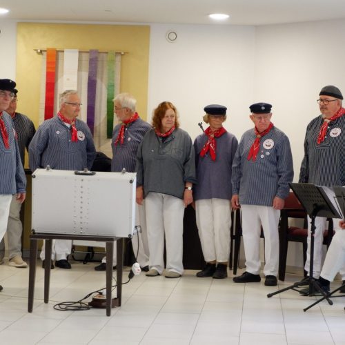 Die Frauen und Männer vom Shanty Chor stehen im Halbkreis und singen.