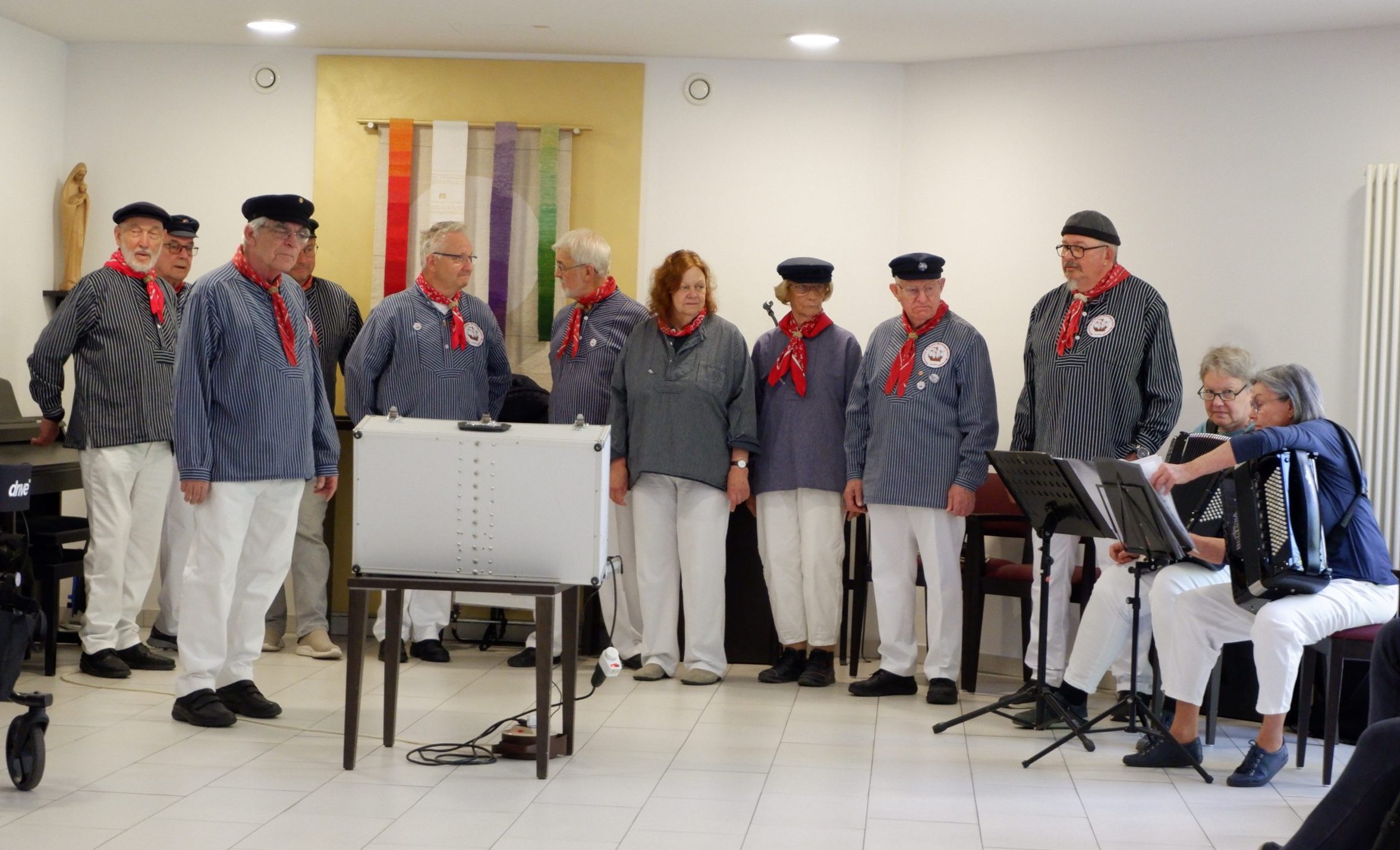 Die Frauen und Männer vom Shanty Chor stehen im Halbkreis und singen.